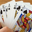 Hand holding queen of spades, king of spades, ace of spades, jack of clubs and jack of spades cards