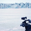 A man in a snow environment uniform with a mechanical device in an arctic landscape.