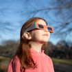 Photo of little girl wearing a hoodie and eclipse glasses