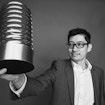 A photograph of Thomas Lin holding a Webby Award.