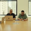 A group of people sitting around a table with computers in front of them