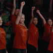 kids in red shirts with their hands raised