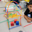 Boy sitting in front of building blocks and sticks